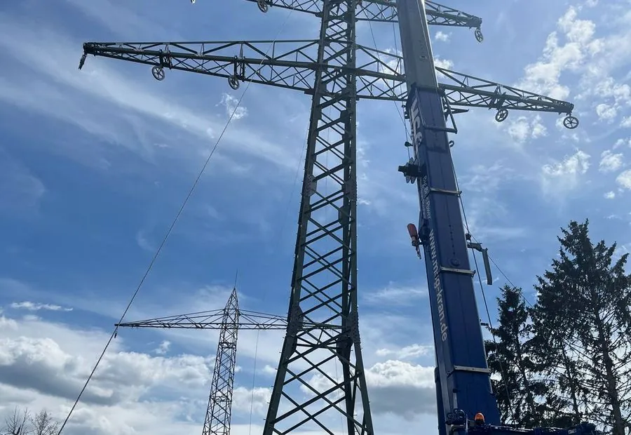 Kran bei der Montage eines Hochspannungsmastes